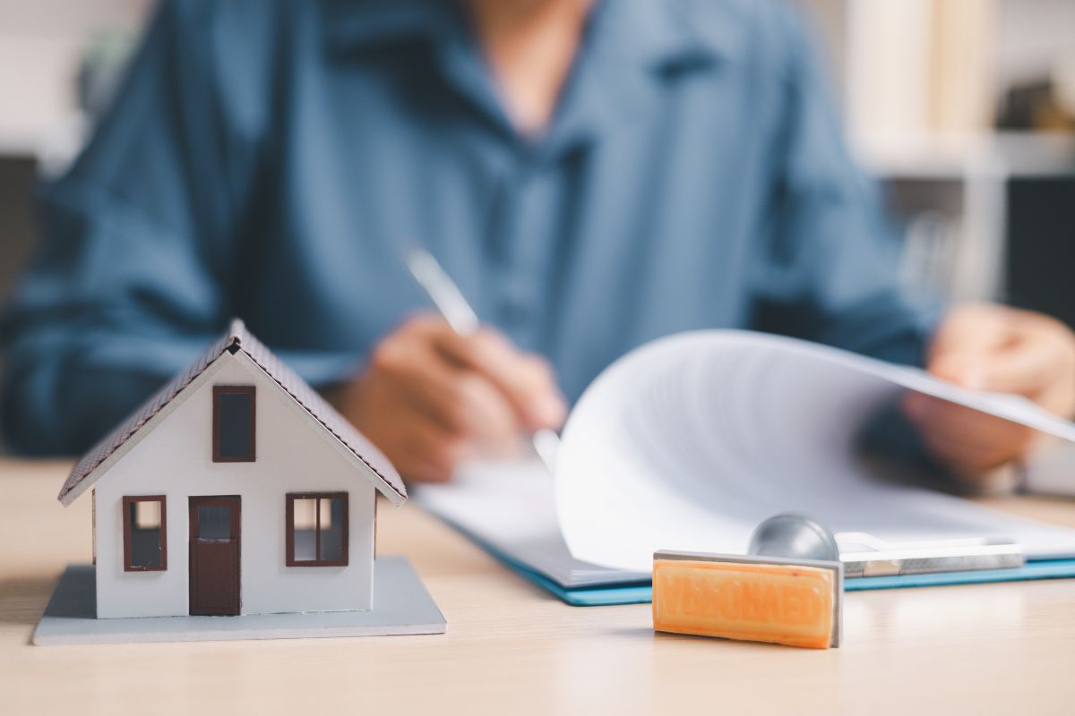 Mortgage broker reviewing home loan paperwork beside a model house